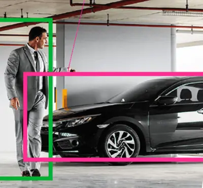 Camera view of a car park: a person and a car marked with detection boxes
